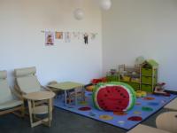 Eltern-Kind-Zimmer Spielecke für Kinder mit gemütlichem Teppich und Regalen, in denen sich Spielsachen und Kinderbücher befinden.