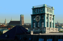 Uhrenturm der TU München vor dem Panorama der Münchner Frauenkirche