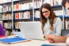 Studentin mit Laptop lernend in der Bibliothek