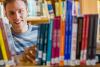 Student hinter einem Buchregal